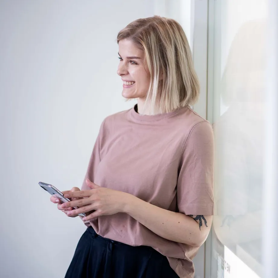 Nainen tutkii kännykällä talousneuvonnan hyötyjä