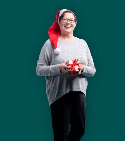Työntekijä tonttulakki päässään ja joululahja käsissään