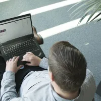 Mies lukee tietokoneelta nettovarallisuudesta.